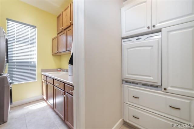 interior space featuring sink, stacked washer / dryer, and light tile patterned flooring