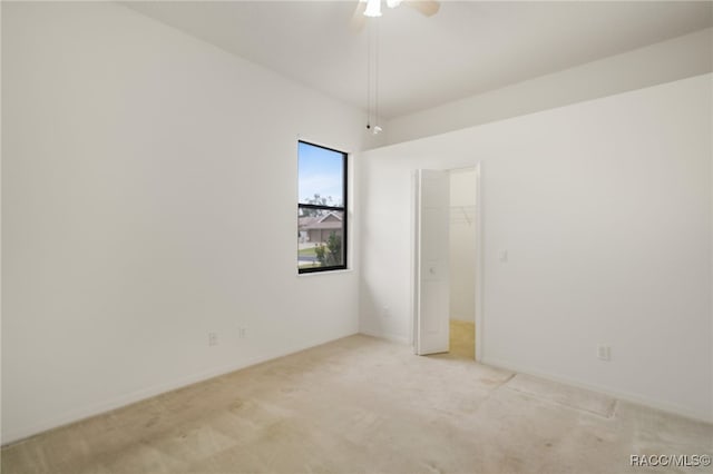 unfurnished bedroom with baseboards, a closet, a walk in closet, and light colored carpet