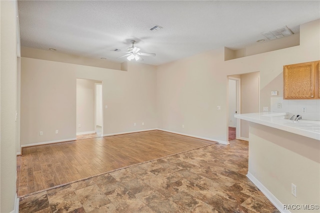 unfurnished living room featuring light wood finished floors, visible vents, ceiling fan, a textured ceiling, and baseboards