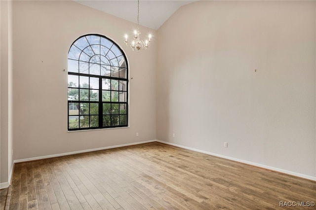 unfurnished room featuring a chandelier, lofted ceiling, baseboards, and wood finished floors