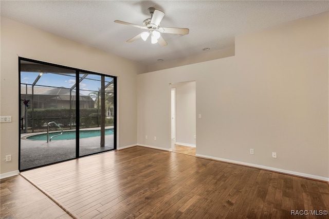 empty room featuring wood-type flooring, baseboards, ceiling fan, and a textured ceiling