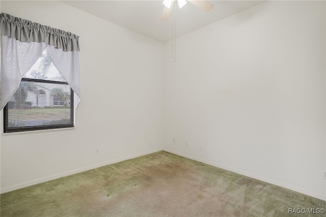 carpeted empty room featuring ceiling fan and baseboards