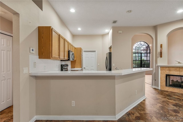 kitchen with visible vents, a peninsula, appliances with stainless steel finishes, and tile counters