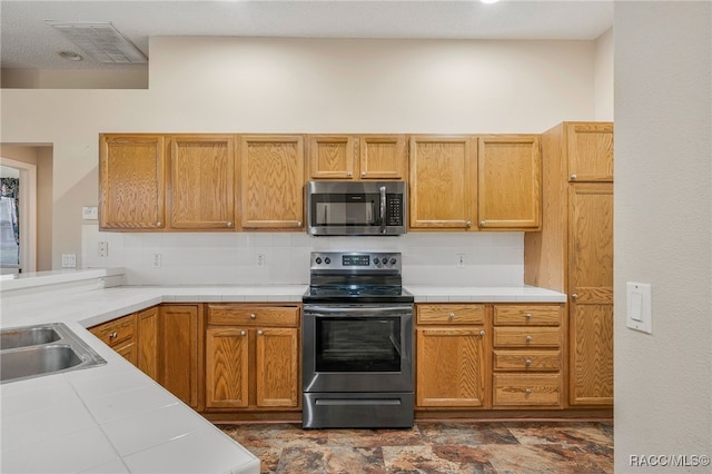 kitchen with visible vents, stainless steel appliances, a sink, and tile counters