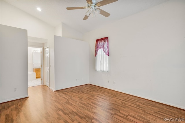 unfurnished room with lofted ceiling, ceiling fan, wood finished floors, and baseboards