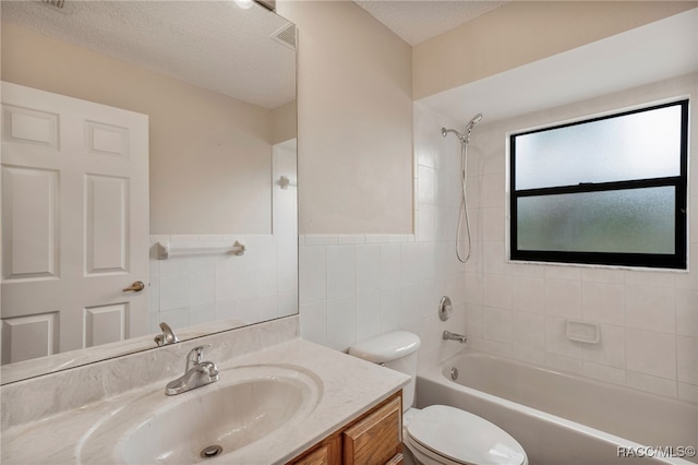 bathroom with shower / bath combination, toilet, a textured ceiling, vanity, and tile walls