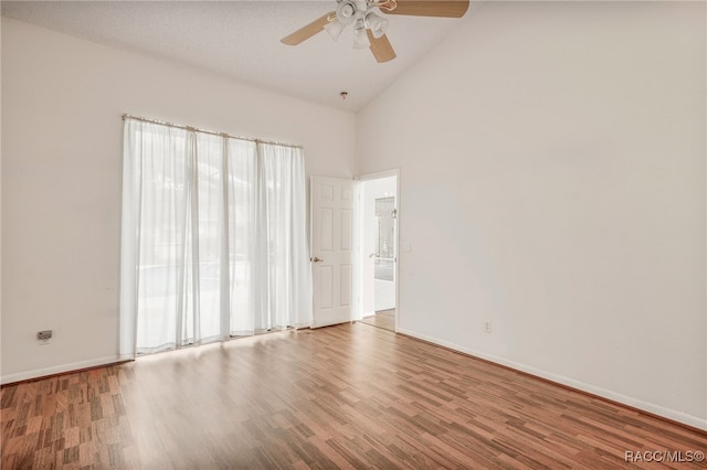 unfurnished room featuring ceiling fan, high vaulted ceiling, wood finished floors, and baseboards