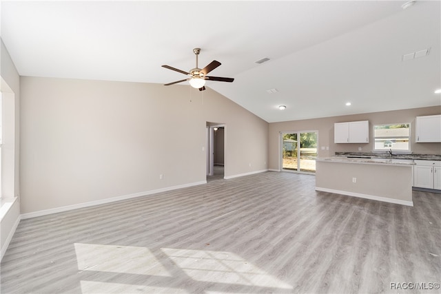 unfurnished living room with ceiling fan, vaulted ceiling, and light wood-type flooring