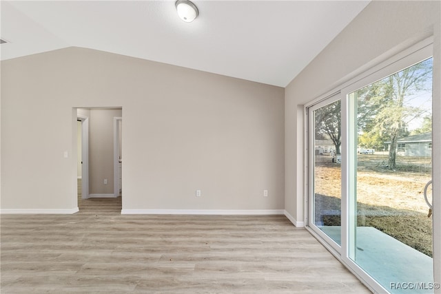 spare room featuring light hardwood / wood-style floors and lofted ceiling