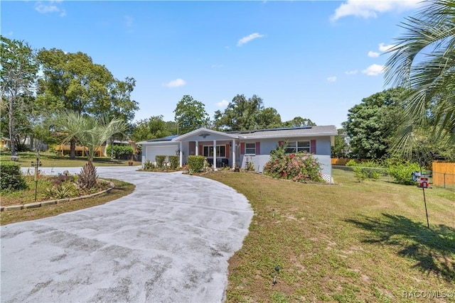 ranch-style home featuring solar panels, a front yard, and a garage