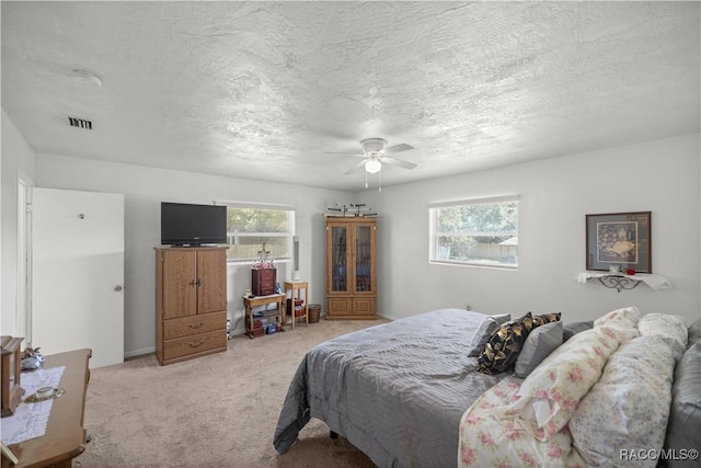 carpeted bedroom with a textured ceiling, multiple windows, and ceiling fan