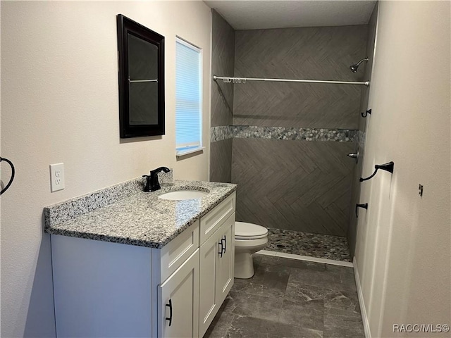 bathroom featuring vanity, toilet, and tiled shower