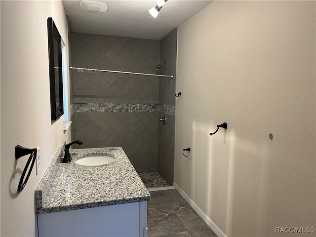 bathroom featuring a textured ceiling, vanity, and walk in shower