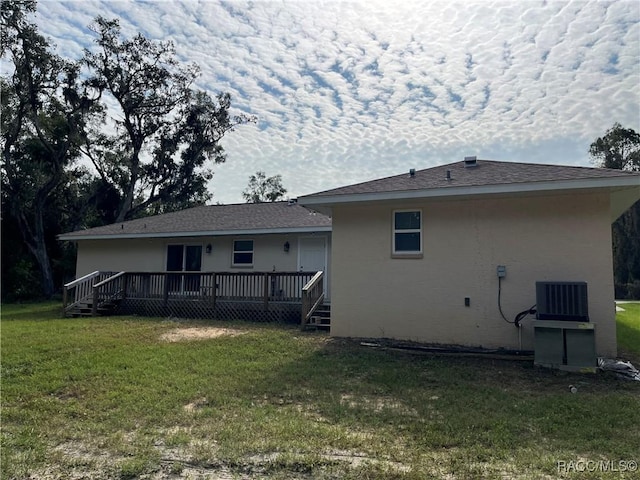 rear view of property featuring a yard, central air condition unit, and a wooden deck