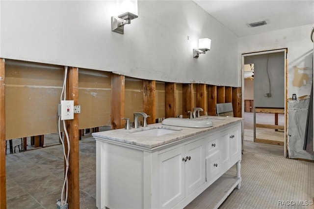 bathroom with visible vents, double vanity, and a sink
