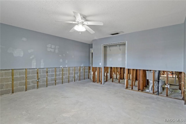 empty room with a textured ceiling, visible vents, ceiling fan, and concrete flooring