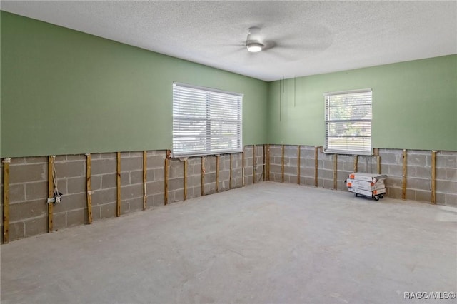 empty room featuring a ceiling fan, wainscoting, and a textured ceiling