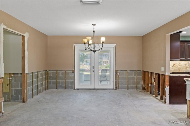 unfurnished room featuring an inviting chandelier, visible vents, french doors, and unfinished concrete flooring