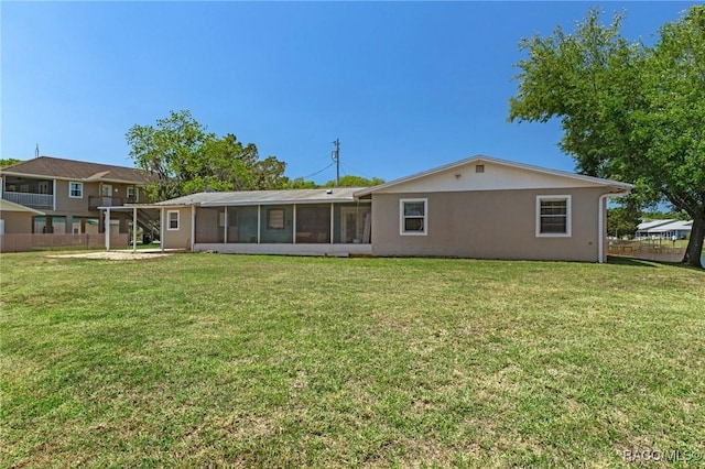 rear view of property with a sunroom, a lawn, and fence