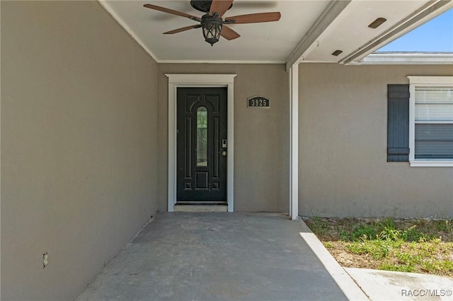 entrance to property with stucco siding and ceiling fan