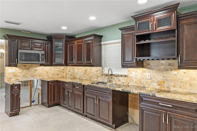 kitchen featuring stainless steel microwave, a sink, concrete flooring, open shelves, and visible vents