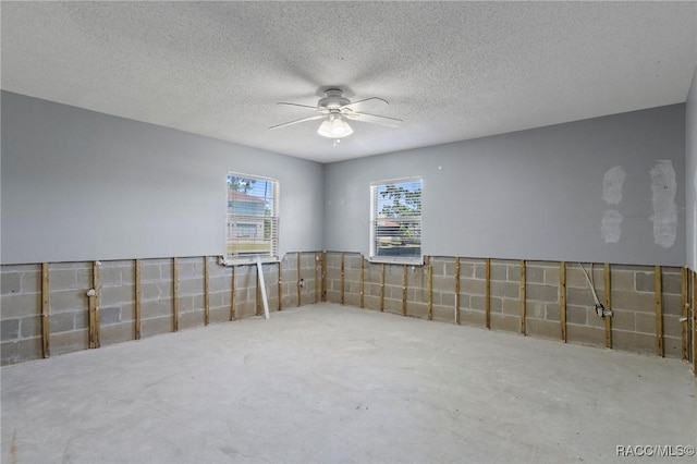 empty room featuring a ceiling fan and unfinished concrete flooring