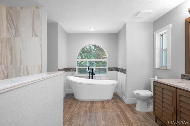 5079 W Pinto Loop, Beverly Hills, FL 34465 - full bathroom featuring a soaking tub, wood finished floors, vanity, toilet, and a wainscoted wall