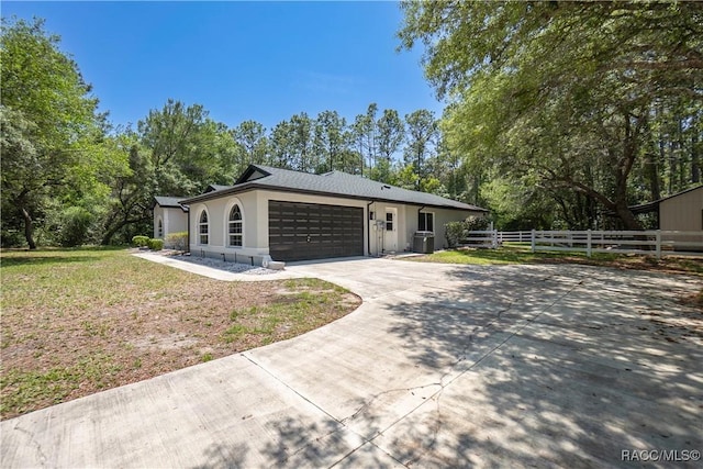 5079 W Pinto Loop, Beverly Hills, FL 34465 - view of home's exterior with concrete driveway, a garage, stucco siding, central air condition unit, and view of wooded area