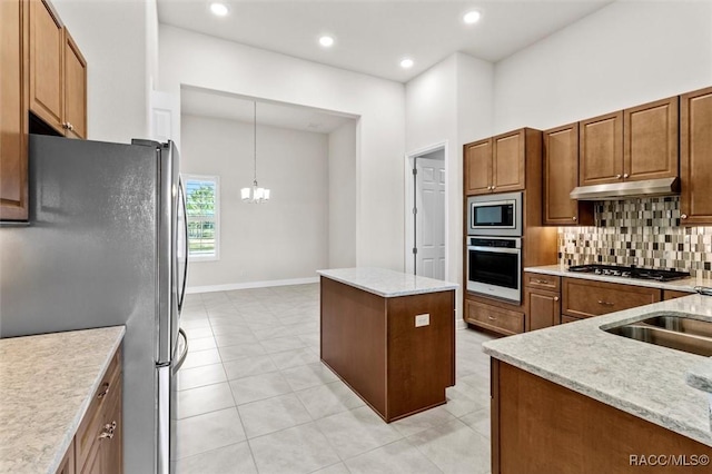 2071 N Buttonwood Loop, Hernando, FL 34442 - kitchen featuring appliances with stainless steel finishes, under cabinet range hood, decorative backsplash, a chandelier, and brown cabinetry