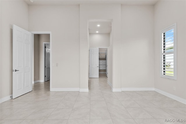 spare room featuring light tile patterned floors and a high ceiling