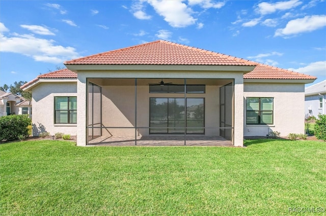 back of property with a lawn, a sunroom, and ceiling fan