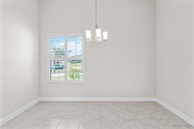 tiled empty room with an inviting chandelier