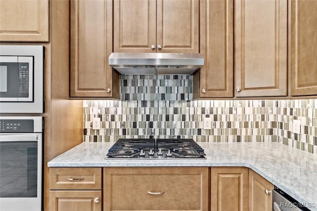 2071 N Buttonwood Loop, Hernando, FL 34442 - kitchen with stainless steel appliances, under cabinet range hood, tasteful backsplash, and light stone countertops