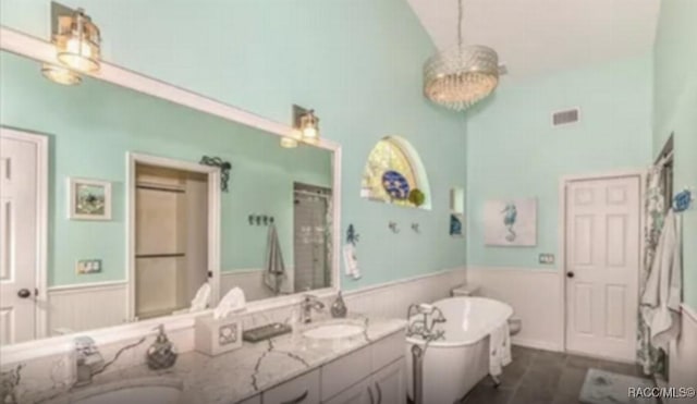 full bathroom with visible vents, a wainscoted wall, double vanity, a freestanding tub, and a sink