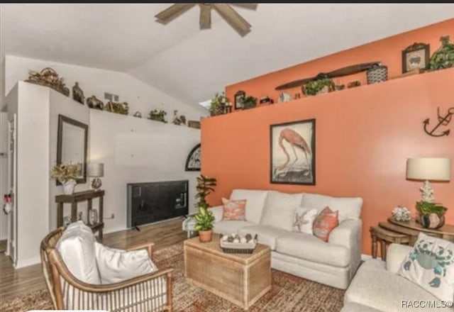 living room with wood finished floors, a ceiling fan, and vaulted ceiling