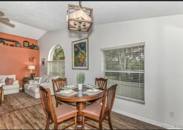 dining area with lofted ceiling, wood finished floors, and baseboards