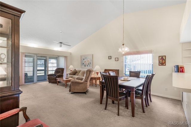 dining space featuring ceiling fan with notable chandelier, light colored carpet, and high vaulted ceiling