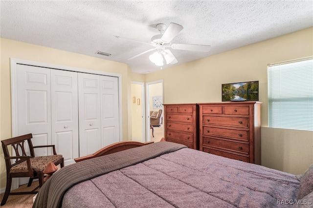 bedroom featuring ceiling fan, a closet, carpet, and a textured ceiling