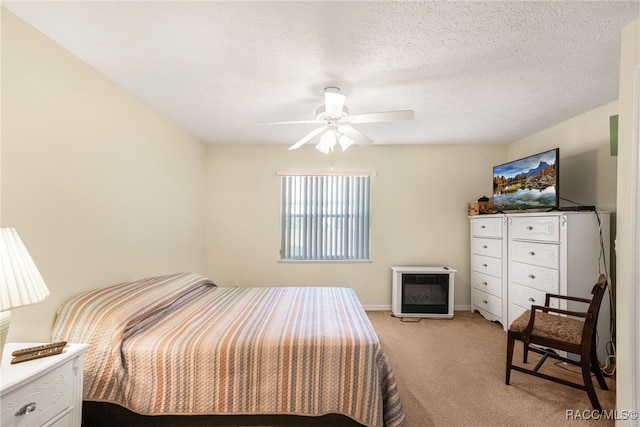 bedroom featuring a textured ceiling, light colored carpet, and ceiling fan