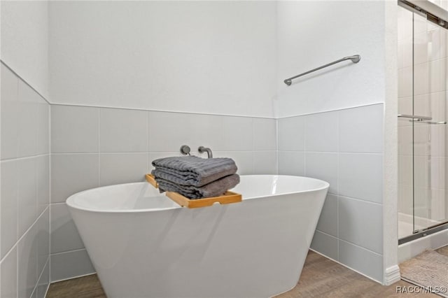 10200 W Waterlander Loop, Homosassa, FL 34448 - bathroom featuring tile walls, wood finished floors, a stall shower, and a freestanding tub