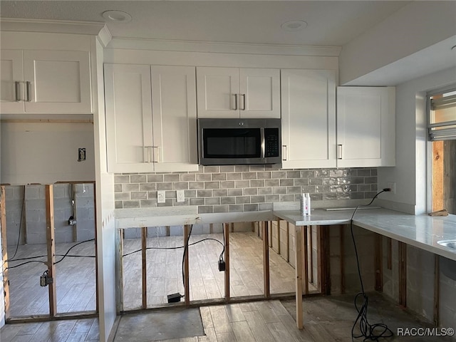 kitchen featuring decorative backsplash, hardwood / wood-style floors, and white cabinets