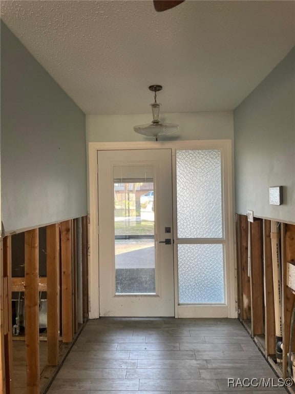 doorway to outside featuring dark hardwood / wood-style flooring, a textured ceiling, and ceiling fan