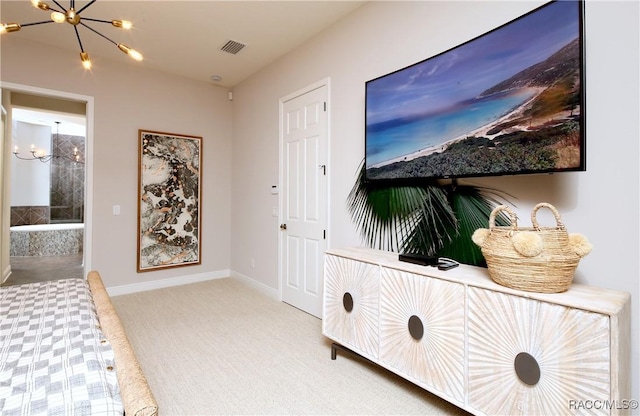 carpeted bedroom featuring ensuite bathroom and an inviting chandelier