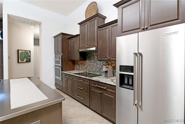 kitchen with dark brown cabinets, light stone countertops, backsplash, and appliances with stainless steel finishes