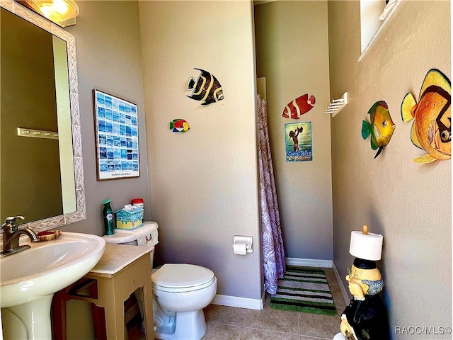 bathroom with toilet, tile patterned floors, and sink