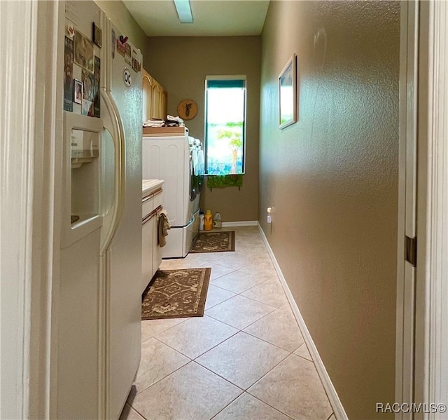 laundry room with washing machine and dryer, light tile patterned flooring, and cabinets