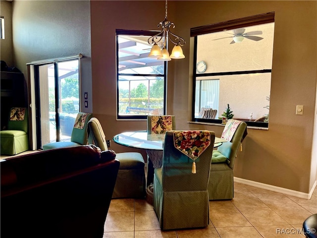 tiled dining room with ceiling fan with notable chandelier