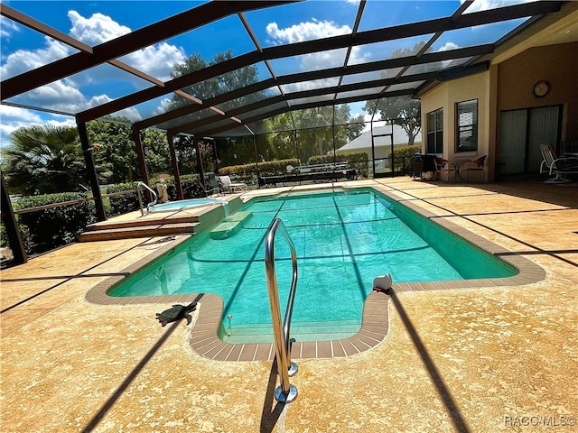 view of swimming pool with glass enclosure, a patio, and a hot tub