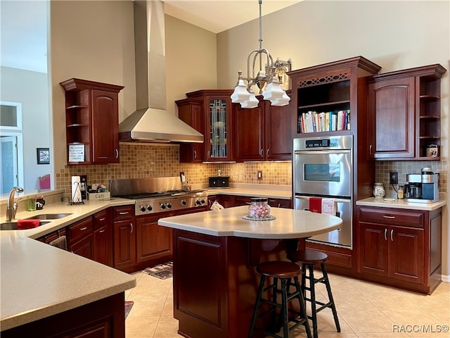 kitchen featuring an inviting chandelier, sink, wall chimney exhaust hood, a breakfast bar area, and stainless steel appliances