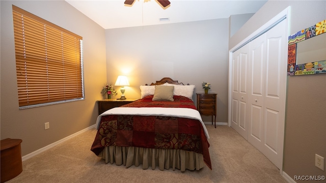 bedroom with ceiling fan, light colored carpet, and a closet